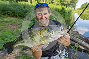 Bass fishing. Fisherman holding largemouth perch fish