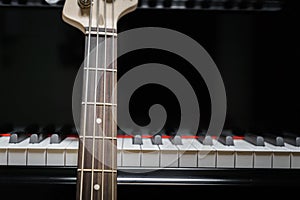 Bass guitar against grand piano keys