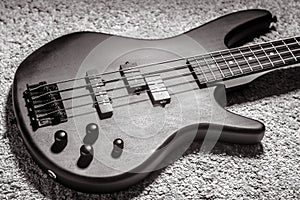 Bass guitar with four strings in black and white. Popular rock musical instrument. View of electric bass on carpet photo