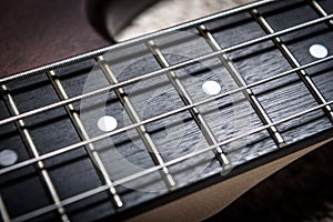 Bass guitar with four strings closeup. Macro photo of textured neck and frets of bass guitar photo
