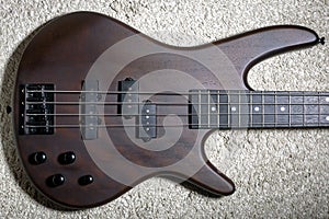 Bass guitar with four strings. Popular rock musical instrument. Top view of brown electric bass on carpet photo