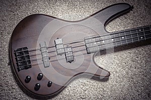 Bass guitar with four strings. Popular rock musical instrument. Top view of brown electric bass on carpet photo