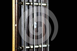 Bass guitar neck isolated on black background, shallow depth of field