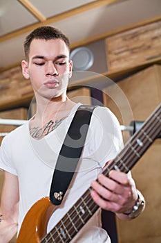 Bass player with tattoo standing with his guitar