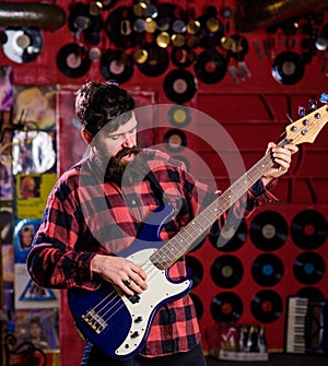 Bassist concept. Man s holds bass guitar, play music in club atmosphere background. Musician, artist play electric