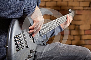 Bassist is playing the bass in front of brick wall