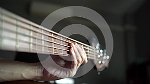Bassist using fingers to pressing strings on the bass` neck