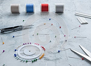 Basting pins with colored heads, a sewing ripper, chalk for cutting, spools of thread, large tailor's scissors.