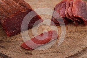 Basturma, dried tenderloin of beef meat, thinly sliced, on a flat wooden board, Isolated on white background