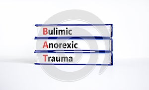 BAT bulimic anorexic trauma symbol. Concept words BAT bulimic anorexic trauma on books on a beautiful white table, white