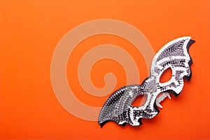 Bat-mask and vampire fangs on an orange background