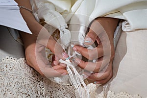 A bat mitzvah holds the tzitzit strings of her prayer shawl