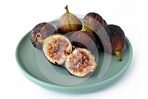 A batch of fresh figs on a light blue plate, isolated