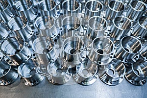 A batch of shiny aluminium aerospace parts made with cnc machine - close-up with background blur, industrial backdrop