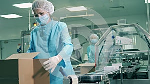 Batches of pills are getting packed into boxes by a female worker