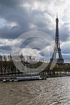 A bateau-mouche on the Seine near the Eiffel Tower on a day with dramatic sky, Paris, France