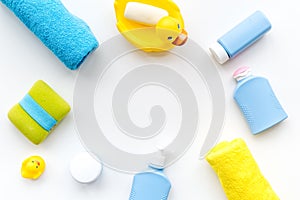 Bath accessories for kids. Yellow rubber duck, soap, sponge, brushes, towel on white background top view copyspace