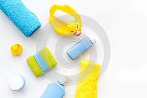 Bath accessories for kids. Yellow rubber duck, soap, sponge, brushes, towel on white background top view copyspace
