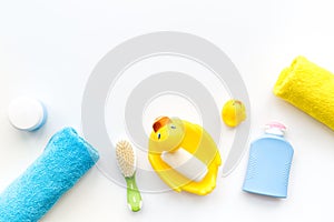 Bath accessories for kids. Yellow rubber duck, soap, sponge, brushes, towel on white background top view copyspace