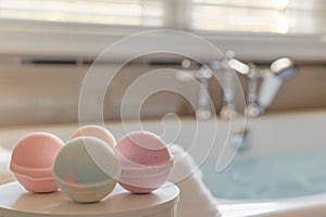 bath bombs on podium, bathtub and faucet out of focus