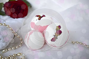 Bath bombs, towel, pearl and red rose on white background