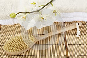 Bath brush on a bamboo mat, towels and a orchid