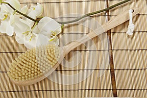 Bath brush on a mat of bamboo and an orchid