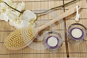 Bath brush, orchid and tealights on a mat of bamboo