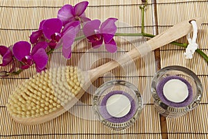 Bath brush, orchid and tealights on a mat of bamboo