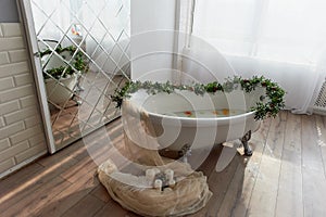 Bath on lion`s paws, decorated with flowers. On the floor are candles.A romantic setting for a date