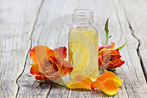 Bath oil and orange rose on wooden background