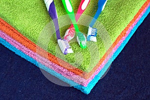 Bath towels of different colors and toothbrushes closeup