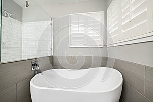 Bath tub in a bathroom with gray walls, a large mirror and windows