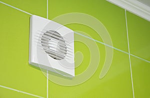 Bath vent fan with green tiles wall. White bathroom ventilation system.
