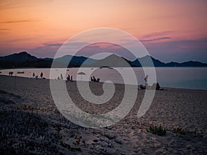 Bathers at sunset on a sandy beach of south Sardinia. photo