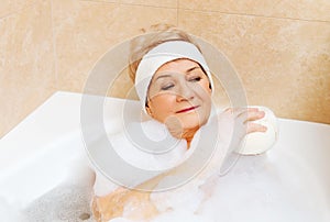 Bathing woman relaxing with sponge