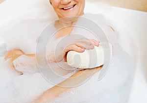 Bathing woman relaxing with sponge