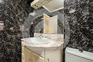 Bathroom with anonymous style black tiles with which they have covered the floor and walls and that tire the eyes and marble