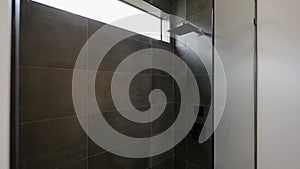 Bathroom area with glass shower cabin and grey granite tiles. Modern minimalistic interior with walk in shower, built-in