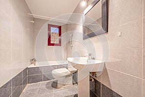 bathroom with bathtub, mirror with rectangular frame attached to the wall, two-tone tiles and white toilets