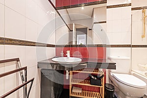 Bathroom with black marble countertop, red details on the tiles