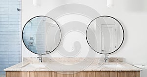 A bathroom with circular mirrors, granite countertop, and wooden cabinet.