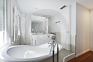 Bathroom with claw-foot bathtub, white wooden furniture with built-in mirror and white radiator towel rail and tiled tiles