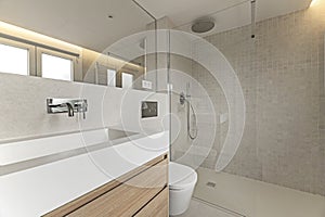 Bathroom corner with floating white oak wood furniture with marble structure on the sink, mirror integrated into the wall