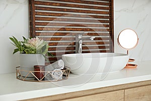 Bathroom counter with stylish vessel sink and small mirror. Interior design