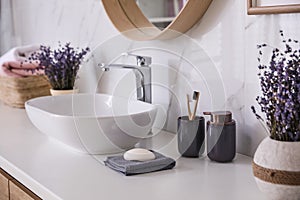 Bathroom counter with vessel sink, accessories and flowers. Interior