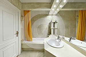 Bathroom with cream marble tiled countertops, large frameless mirro