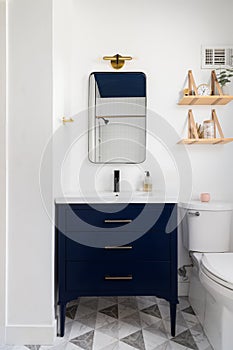 A bathroom detail with a pattern tile floor and dark blue cabinet.