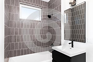 A bathroom with a dark vanity and brown tiled shower.