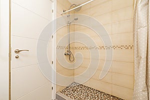 Bathroom with an elongated shower cabin with tiled floors and a white wooden door